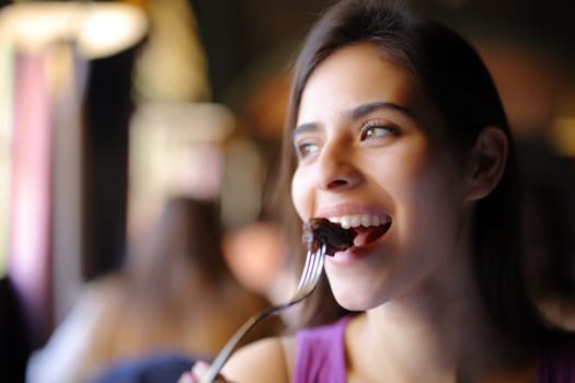 Happy woman eating meat using fork in a restaurant