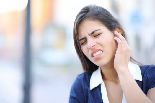 Stressed woman complaining suffering earache in the street