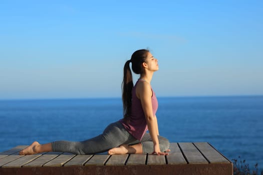 Profile of a woman doing yoga exercises on the beach