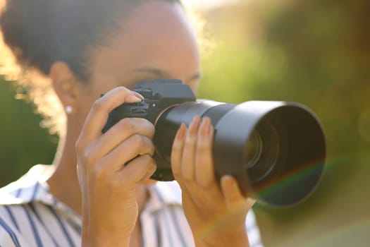 Black photographer taking pictures with mirrorless camera in a park