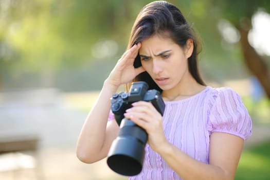 Worried photographer checking result on camera in a park