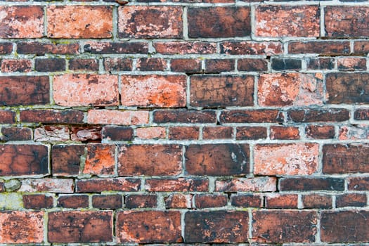 Full framed frontal view of a weathered brick wall, with two different side formats and intact joints.