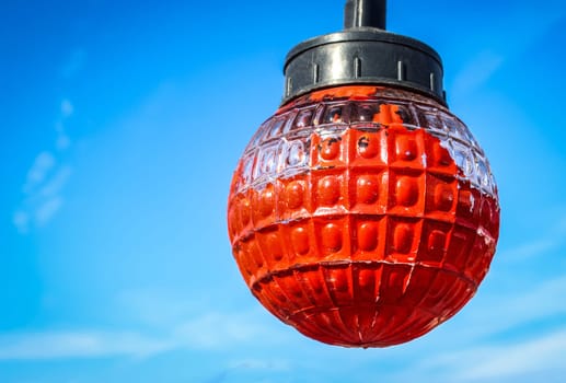 Red light bulb and blue sky with clouds