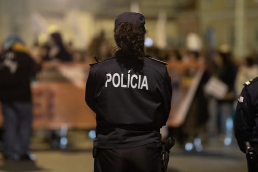 Policewoman guarding the rally at evening. Mid shot