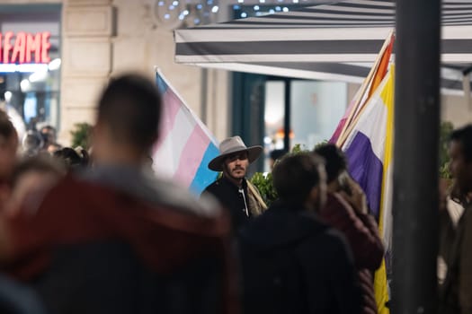 PORTUGAL, LISBON 11-25-2022: the March for the End of Violence Against Women - a man holding transgender flag. Mid shot