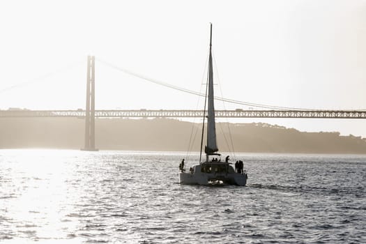Sailboat sails the river heading for the bridge. Mid shot