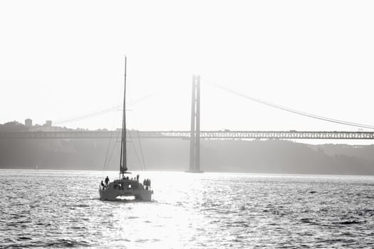 People standing on a sailing yacht sailing along the river towards the bridge. Mid shot