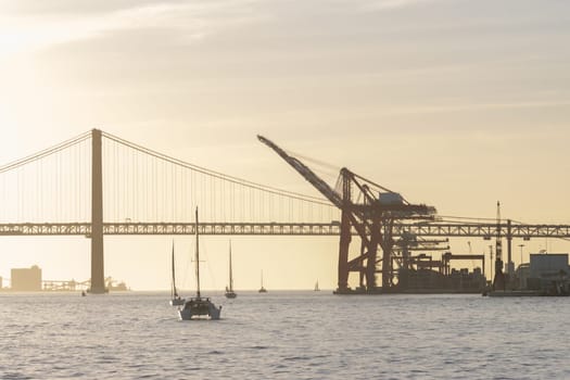 Sailboat sails down the river at industrial cranes. Mid shot