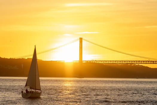Sailing boat floating on the river at an orange sunset. Mid shot