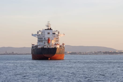 An industrial transport vessel sails on a river. Mid shot