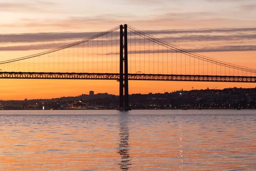 Lisbon and 25th of April Bridge at sunset. Mid shot