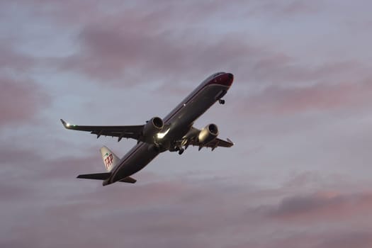 30 November 2022 PORTUGAL, LISBON: a large plane gains altitude in a purple sky. Mid shot