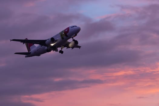 30 November 2022 PORTUGAL, LISBON: an airplane flies in the sky at purple sunset. Mid shot