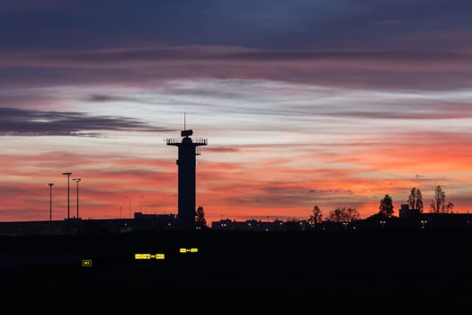 30 November 2022 PORTUGAL, LISBON: Silhouettes of the tower of houses and trees near the airfield at bright sunset. Mid shot