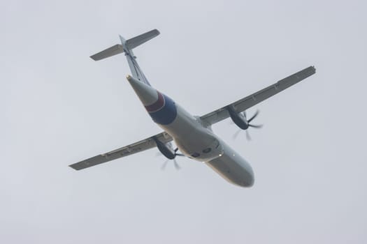 30 November 2022 PORTUGAL, LISBON: A small plane with propellers on its wings takes off into the grey sky. Mid shot