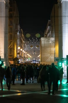 People walk along lisbon's decorated main street. Mid shot