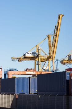 Yellow crane operates in a warehouse in the port. Mid shot