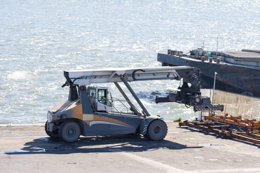 A man working with a lifter in a seaport with connected spreader. Mid shot