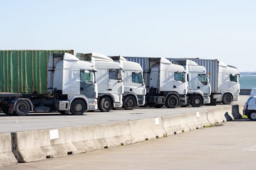Trucks stand in a row near the seaport. Mid shot