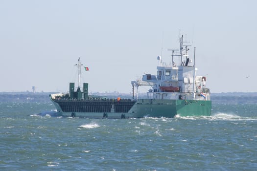 A big portuguese cargo ship sails the sea. Mid shot