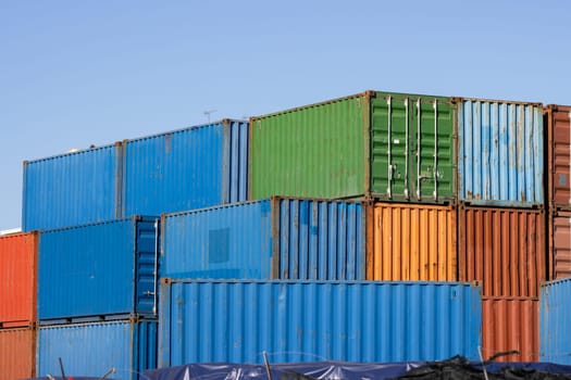 Multicolored cargo containers on a blue sky background. Mid shot