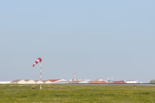 A green field and a warning sign in the middle of it - blurred warehouses in the background. Mid shot
