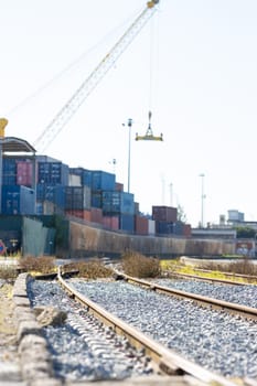 Railways near the warehouse with a bunch of containers in the open air. Vertical shot
