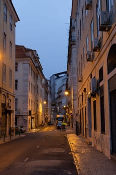 PORTUGAL, LISBON 12 december 2022: a European street and a couple of people in reflective vests in the early morning. Mid shot