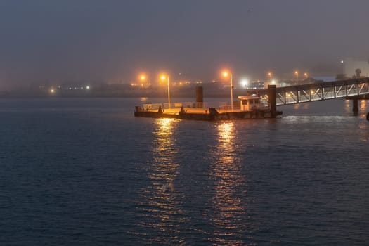 A pier by the foggy calm sea in the late evening. Mid shot