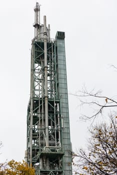 Oil and gas processing tower on a background of grey sky. Vertical shot