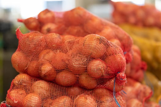 Kilograms of onions in a net at the market. Mid shot