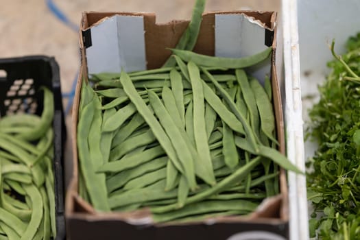 Fresh green string beans in a box at the market. Mid shot