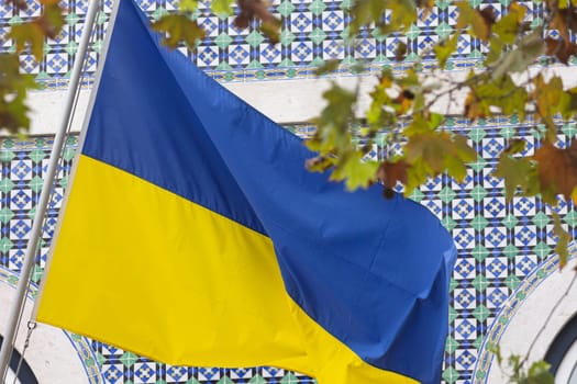 Blue-yellow flag of Ukraine somewhere in the city. Mid shot