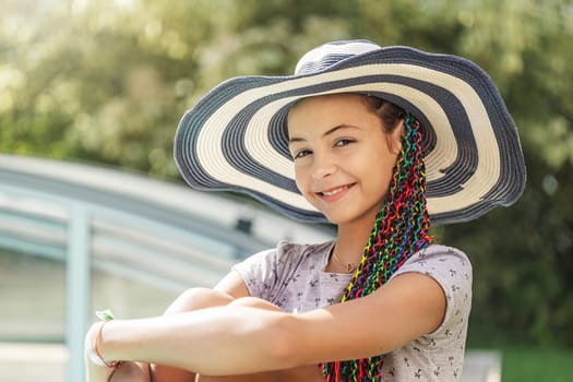 Smiling cute little girl is posing in a straw hat. Horizontally.