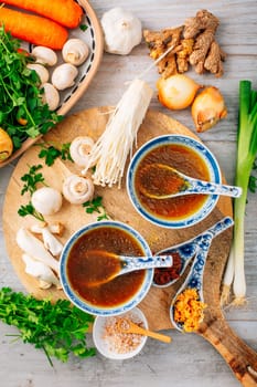 Miso, ramen or vegetable broth with ingredients on wooden background