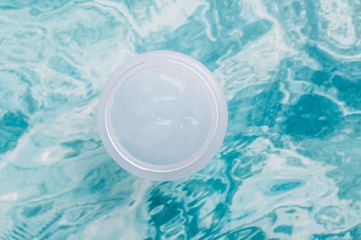 Beauty cream jar and bright light blue water. Moisturizing beauty cream, skincare and spa cosmetics. Top view and copy space