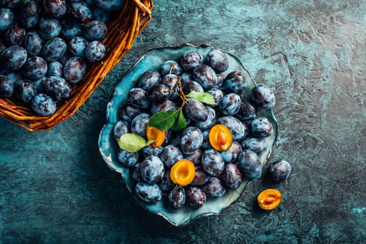 Freshly picked plums in a bowl and basket. Organic food and harvesting concept