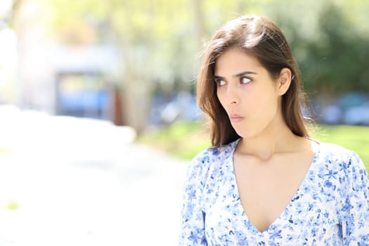 Perplexed woman looking at side standing in the street