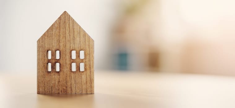 Figurine of wooden house standing on the table indoors. Panoramic background.