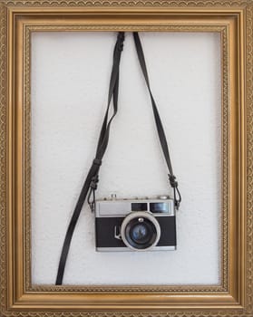Compact vintage camera hanging on the wall inside a picture frame. Film photography concept