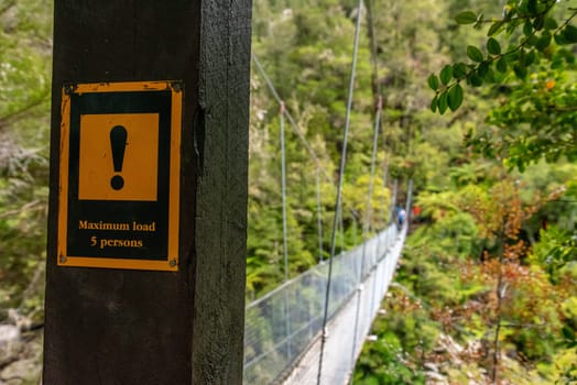 Warning signs about a suspension footbridge in Abel Tasman Cost Track, New Zealand