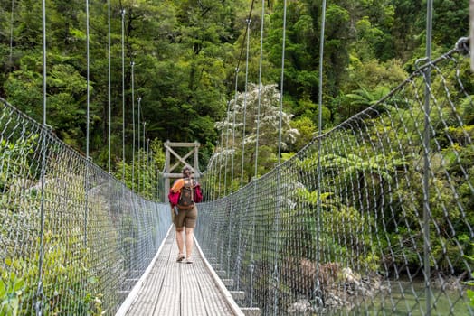 Crossing a suspension footbridge at Abel Tasman Cost Track and enjoying the view, New Zealand