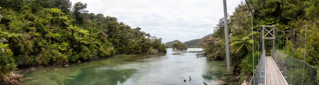 Panoramic view of suspension bridge over a river at Abel Tasman National Park, New Zealand
