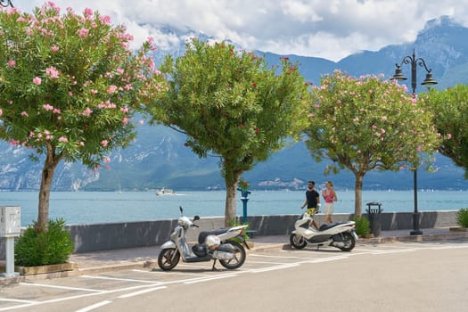 Motor scooters and tourists on the promenade on the shore of Lake Garda, Lago di Garda, in the popular resort of Limone Sul Garda