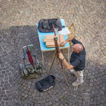 Street painter painting pictures for tourists during his preparations in the old town of Malcesine in Italy