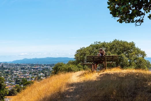 Woman on a bench sitting in a park enjoying the view over Auckland, New Zealand