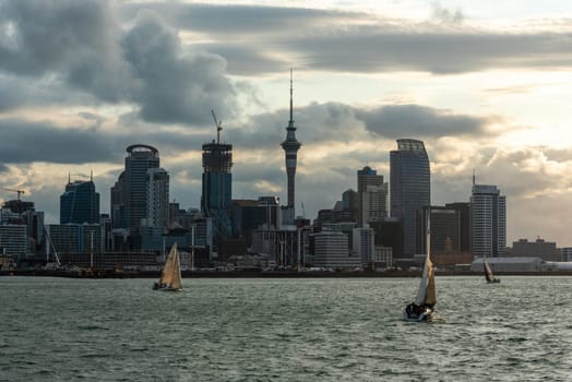 Famous skyline of Auckland Central Business District during sunset, people anjoying the warm summer evening on their sailboats, New Zealand