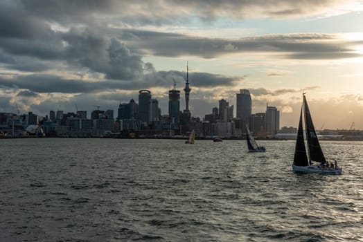 Famous skyline of Auckland Central Business District during sunset, people anjoying the warm summer evening on their sailboats, New Zealand