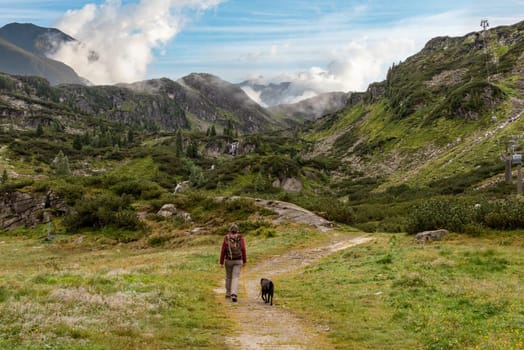 Woman hiking with her dog in the High Tauern National Park, the Austrian alps