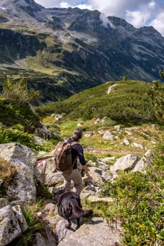 Woman hiking with her dog in the High Tauern National Park, the Austrian alps
